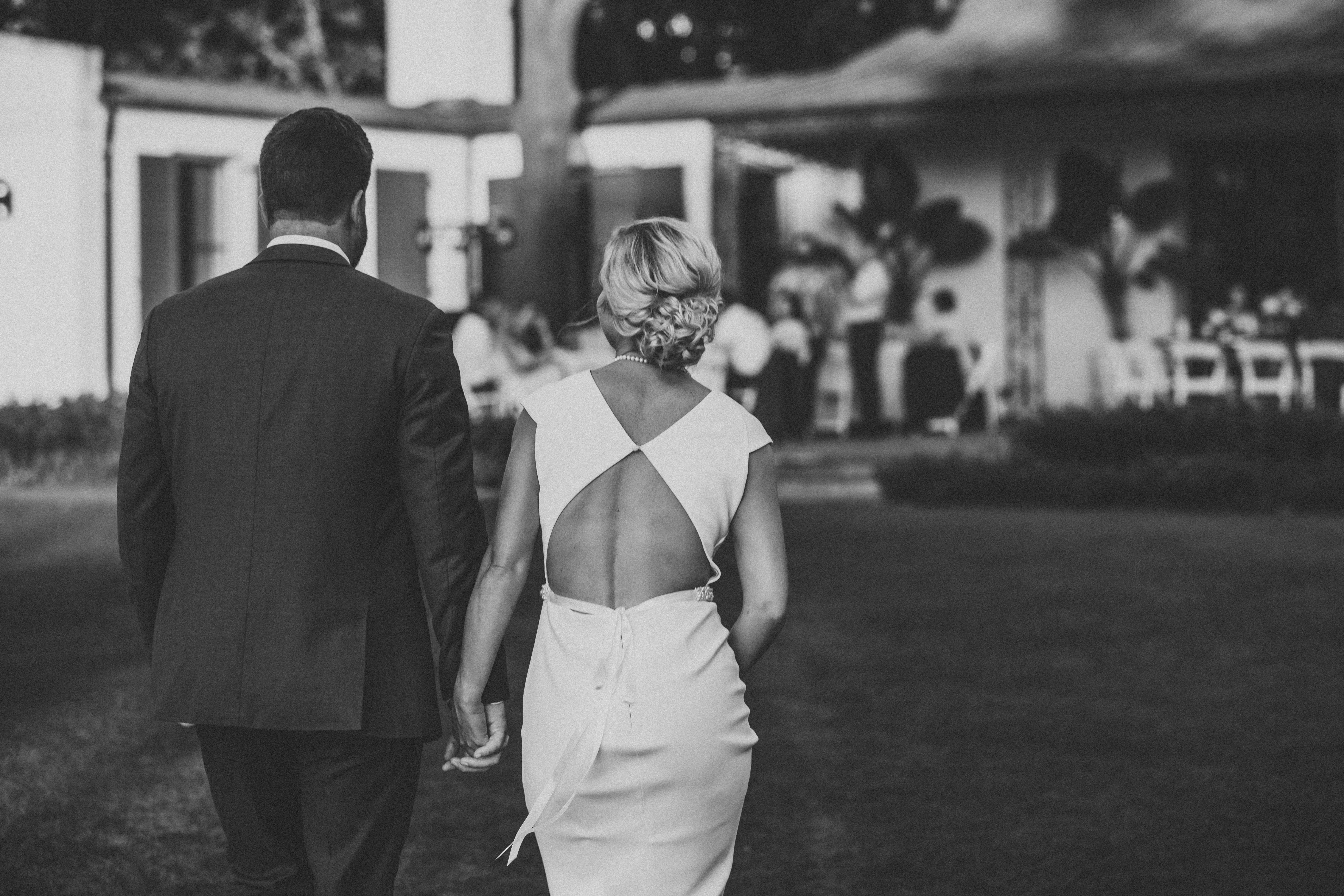 man in black suit jacket holding woman in white dress walking on street